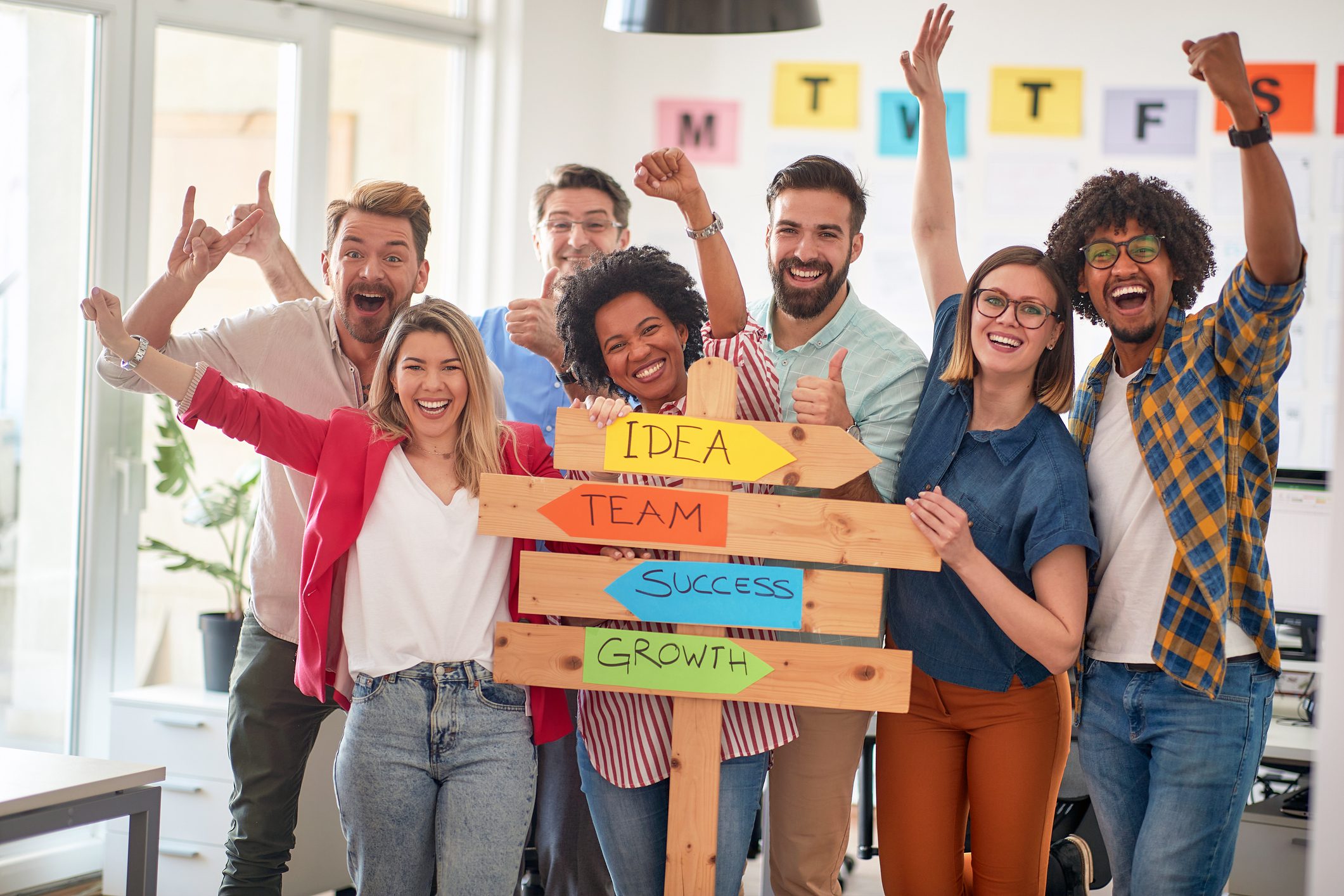 Group of diverse professionals holding a colorful sign about idea, creativity, and growth.